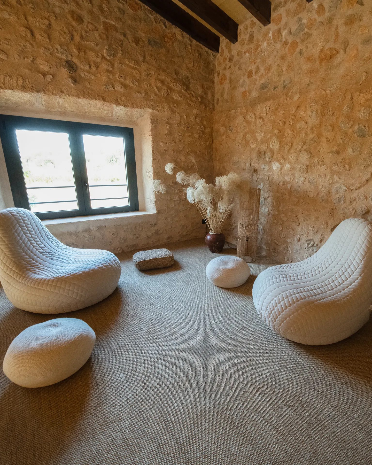 The reading room — stone walls, white sculptural chairs and quiet afternoon light