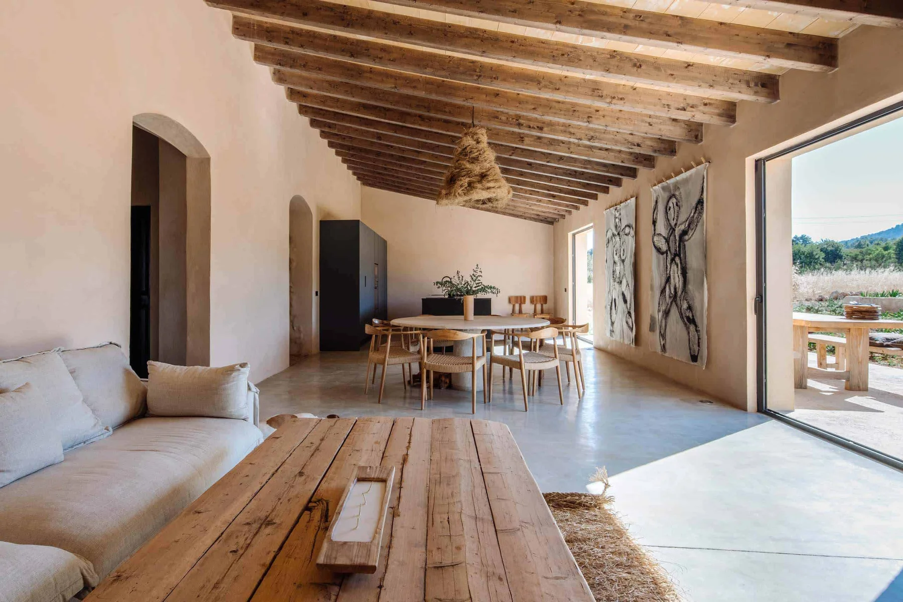 The main living and dining space — beamed ceilings, natural materials, open to the terrace