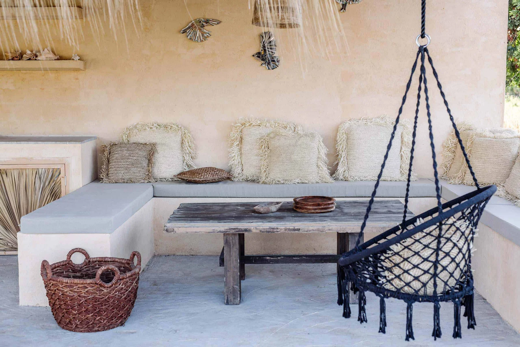 The outdoor lounge — built-in seating, woven cushions and a hanging chair