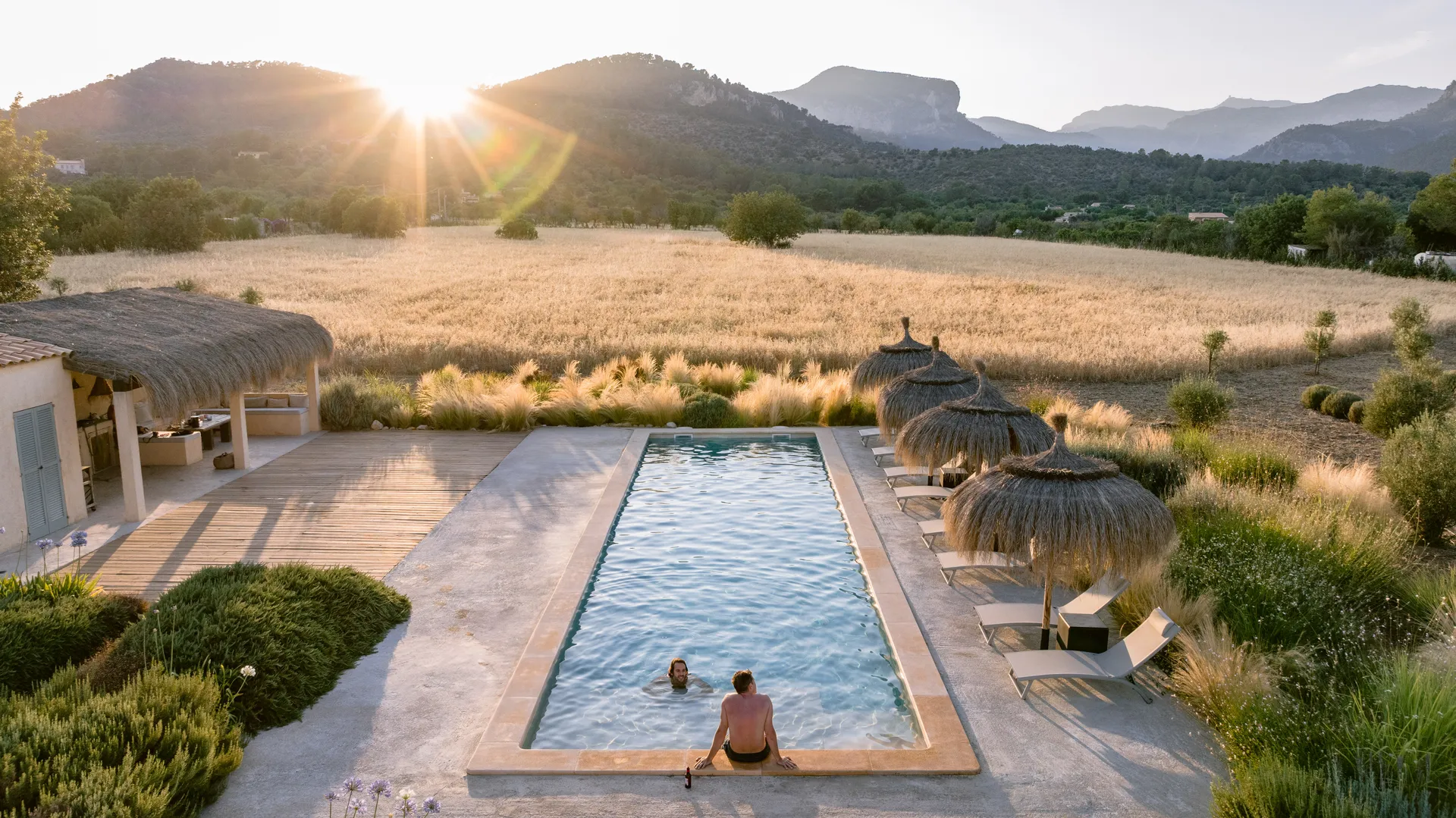 Golden hour at the pool — two guests settling into the evening, mountains glowing beyond