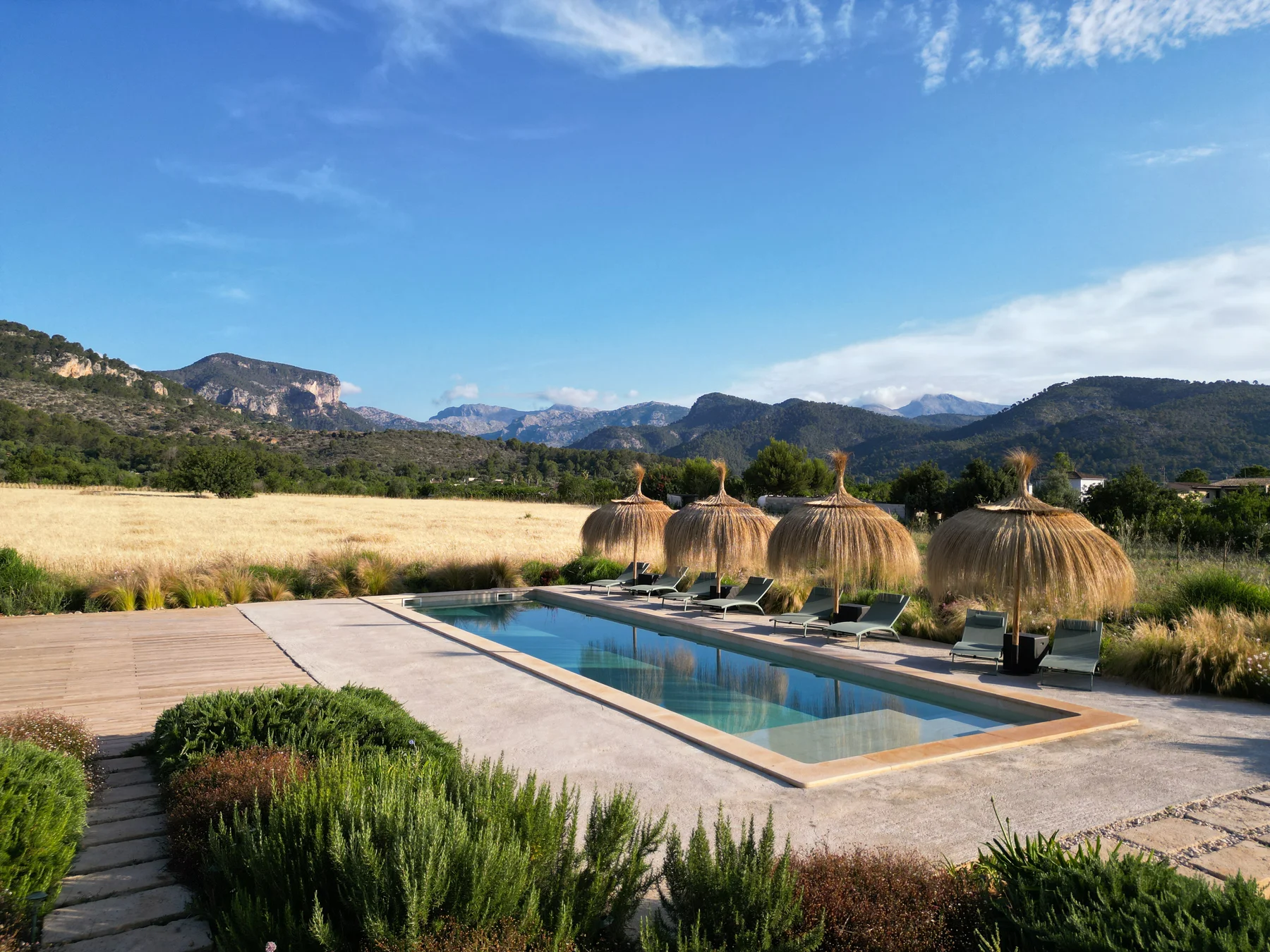 Pool terrace with thatched parasols and the Tramuntana in the background