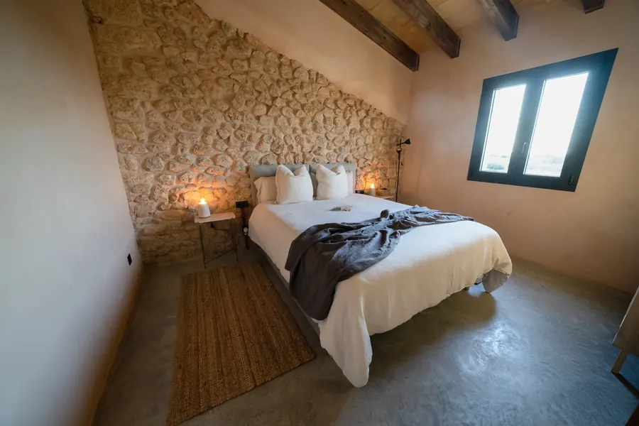 A bedroom at dusk — candlelight, stone and soft linen