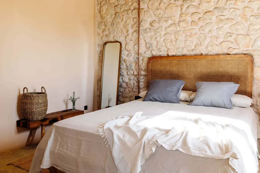 Bedroom with original stone wall — rattan headboard, linen and morning calm