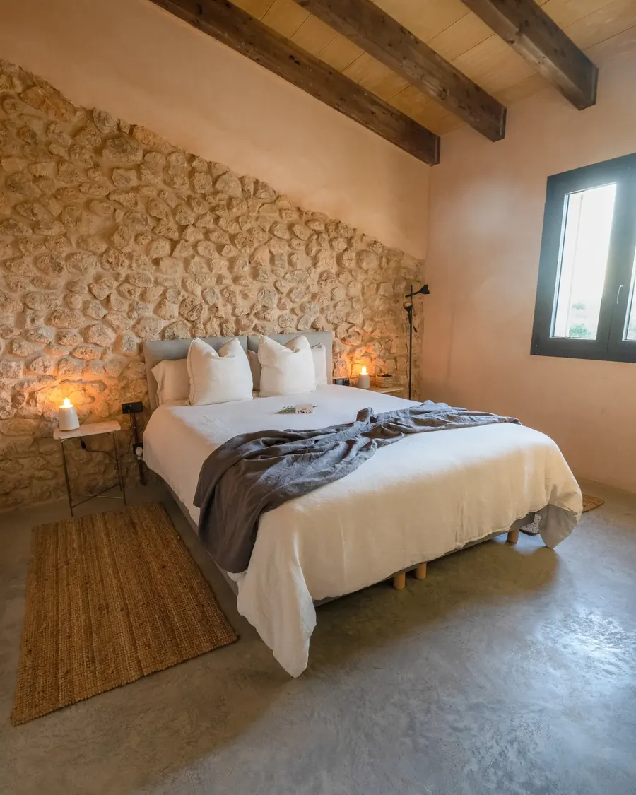 Bedroom — warm tones, stone wall and evening light