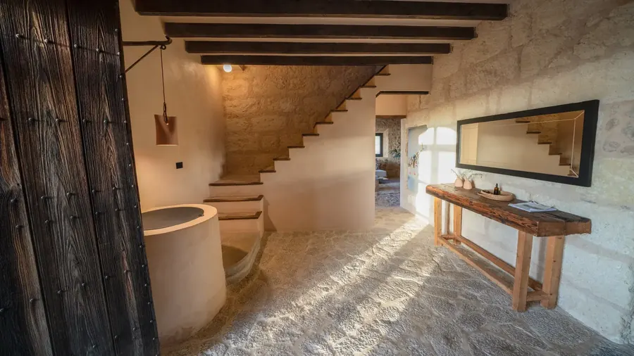 The entrance hall — original stone, a round bath detail and the staircase beyond
