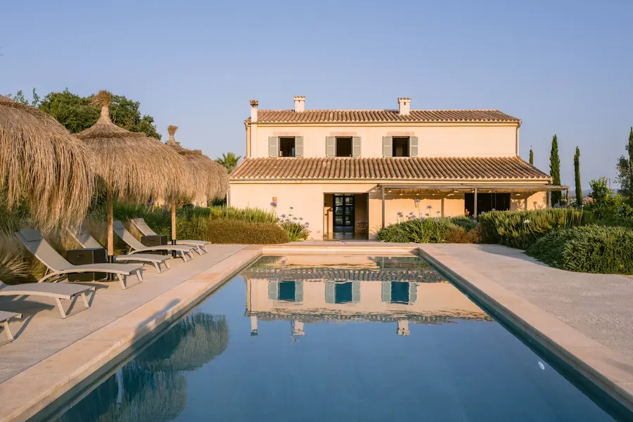 The finca at golden hour — warm stone reflected in the still pool