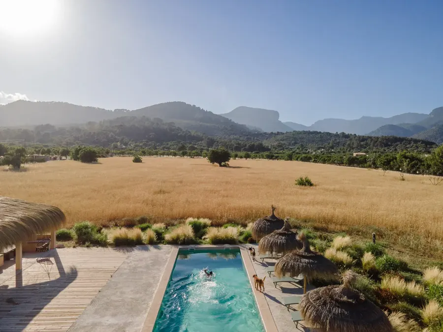 The pool at Casa Mana — golden wheat fields and the Tramuntana mountains beyond